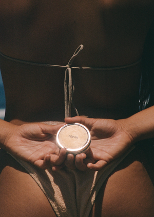 Woman holding Our all natural tinted Surf Balm Sunscreen features broad spectrum SPF 30 sun protection without the use of chemical UV filters, preservatives, emulsifiers, silicones, nano-particles, micro-plastics, animal testing, phthalates or parabens. Crafted with four powerful ingredients which work together to protect and nourish your skin in harsh conditions.